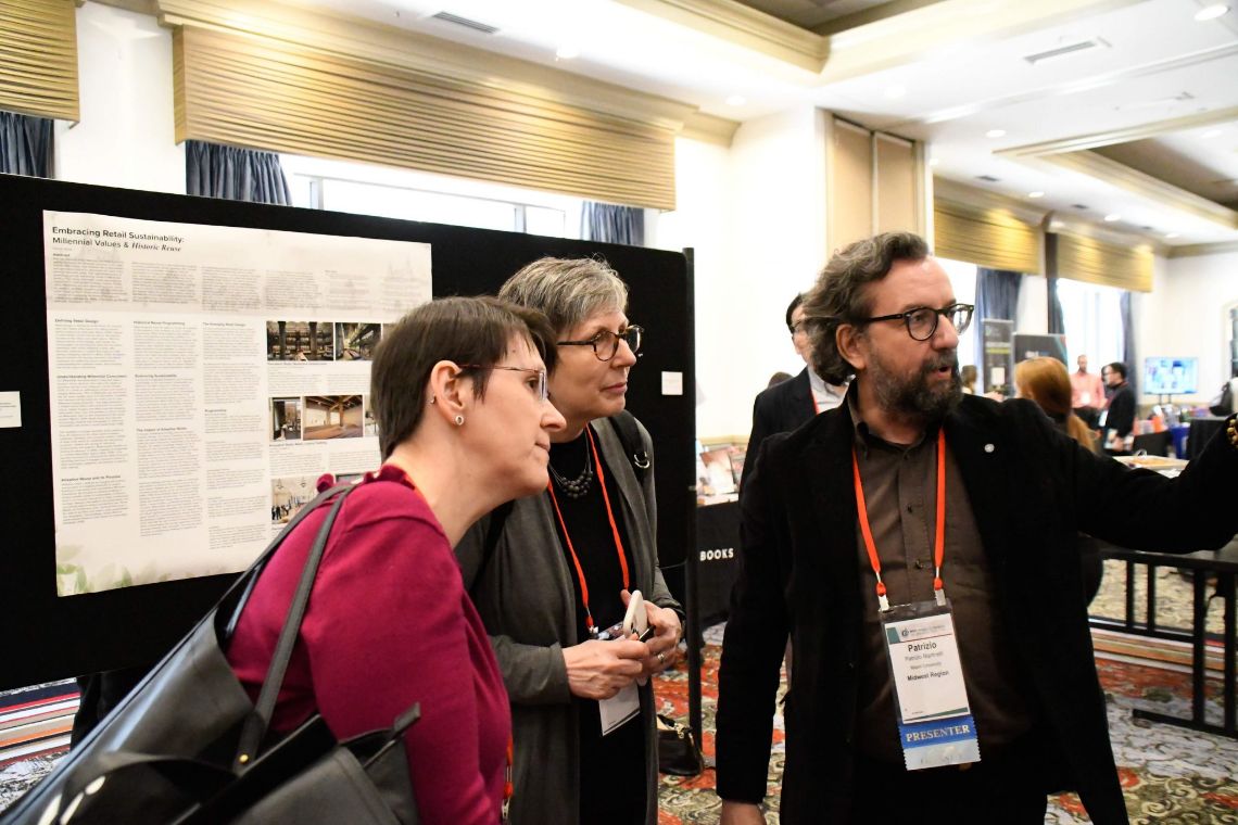 Man talking with two women at a conference