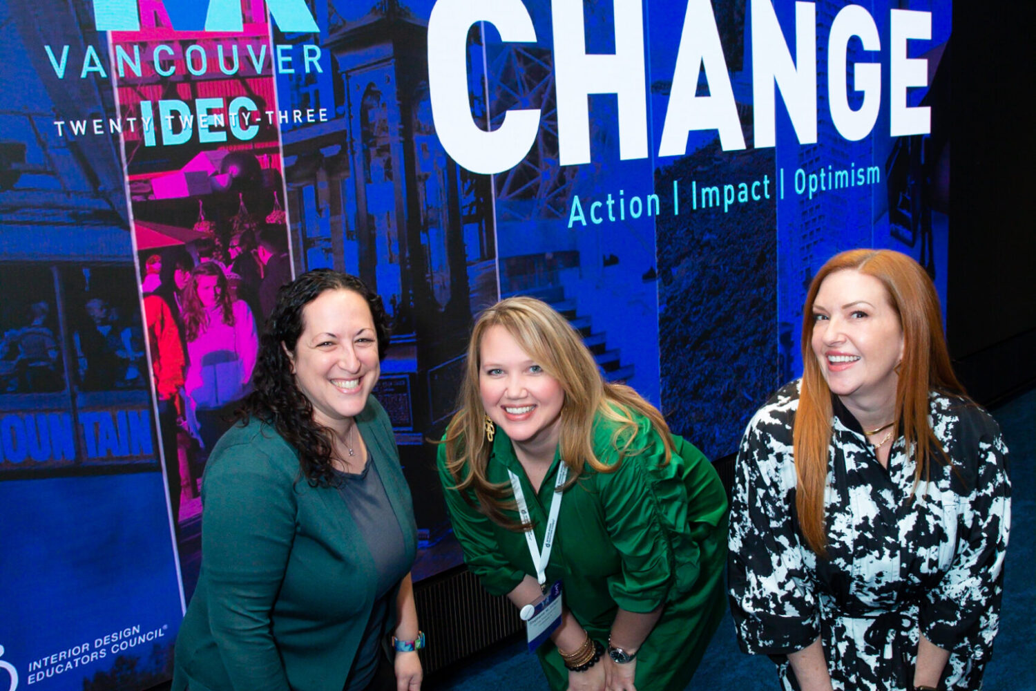 Three women posing in front of conference banner.