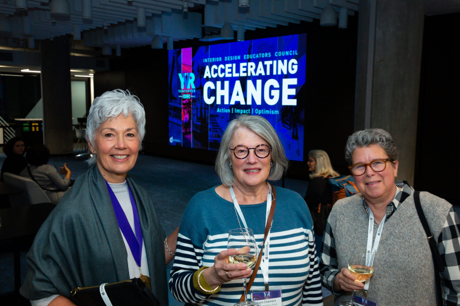 Three women holding wine in conference venue lobby