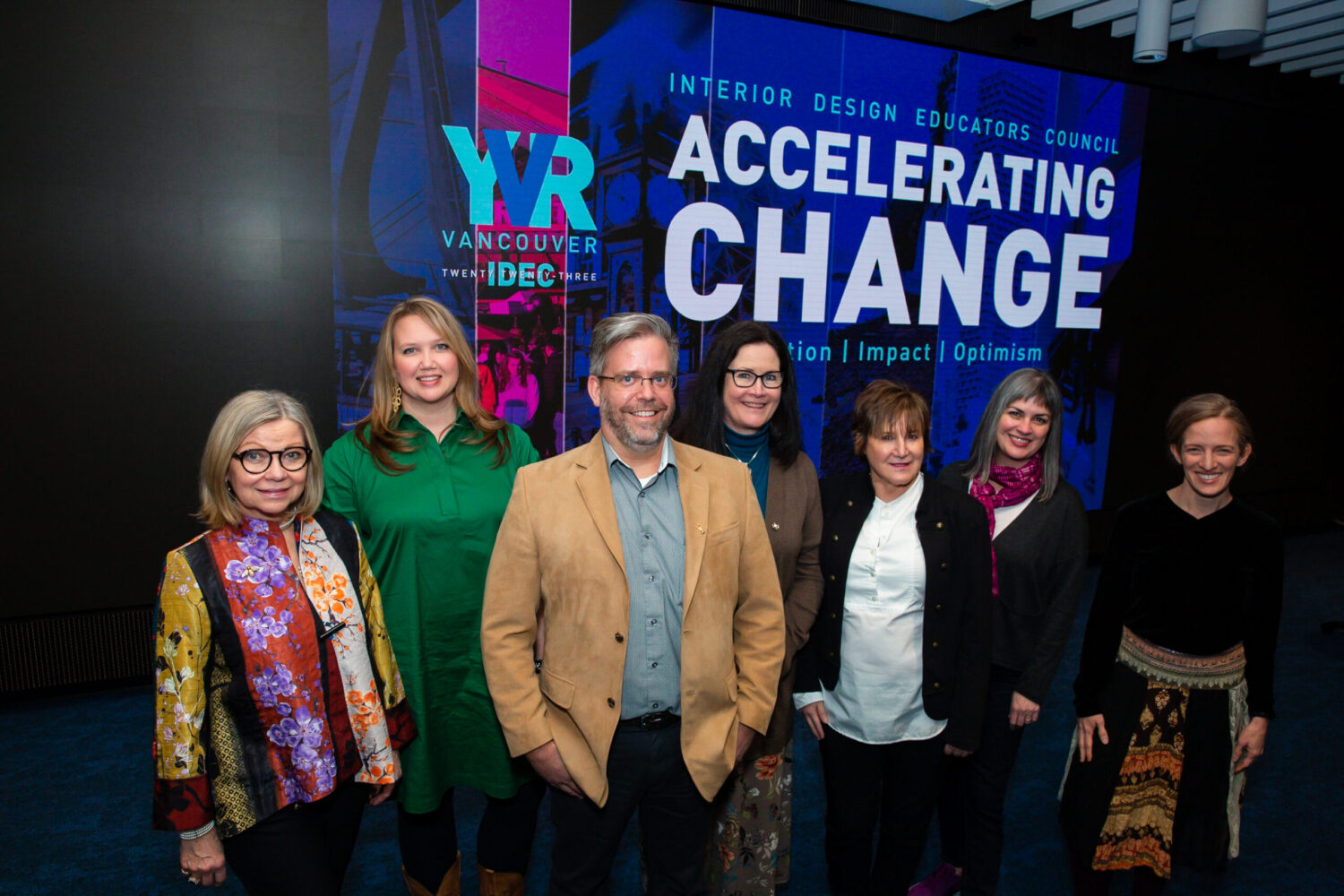 IDEC board members standing in front of Accelerating Change conference banner.