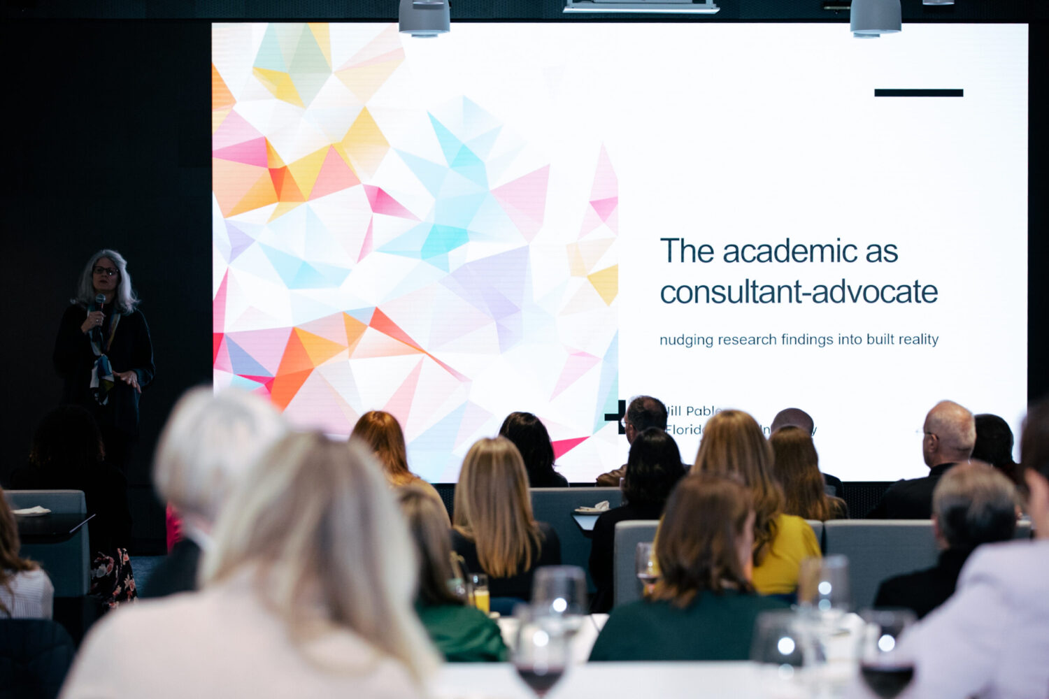 Woman giving presentation titled "The academic as consultant-advocate."