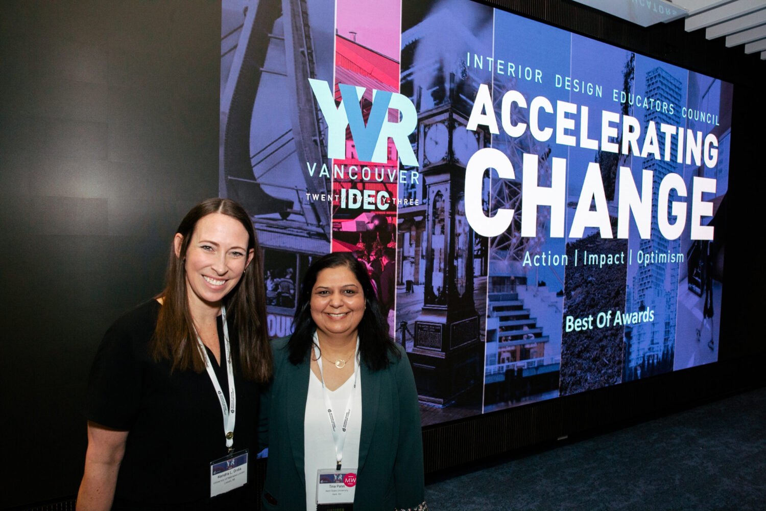 Two women smiling in front of Accelerating Change conference banner.