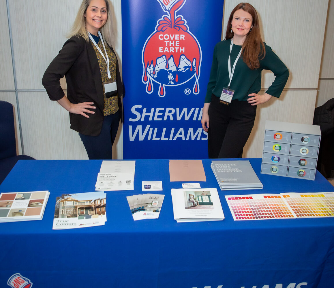 Two women posing in Sherwin Williams booth.