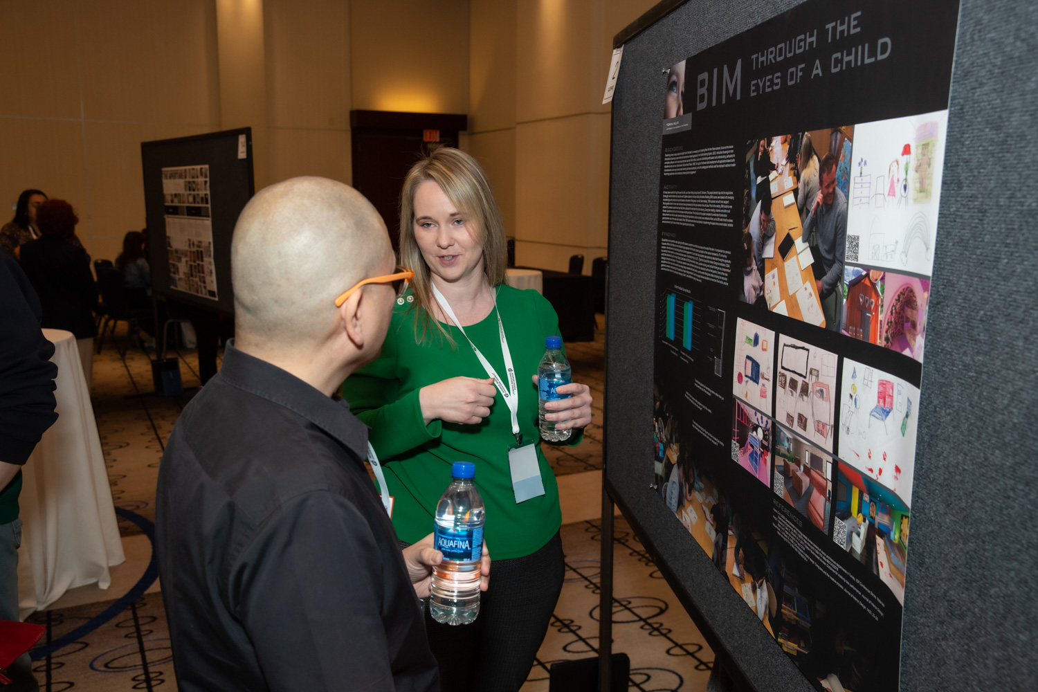 Conference-goers conversing in front of poster.