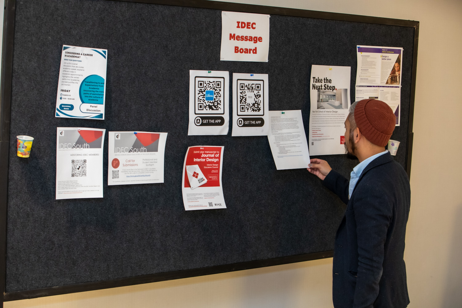 Conference-goer reading paper on bulletin board.