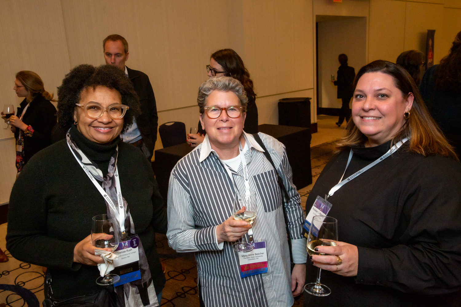 Conference-goers posing while holding wine glasses.